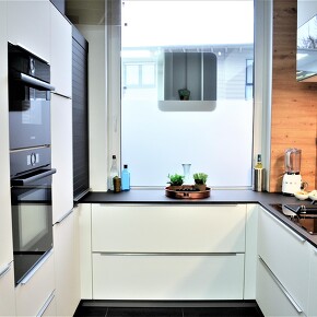 Moderne PerfectSense Küchenfront in schwarz und weiß mit einer Holz Nischenrückwand Moderne PerfectSense Küchenfront in schwarz und weiß mit einer Holz Nischenrückwand