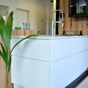 Grifflose mattweiße Kücheninsel mit einer Holz Rückwand Grifflose mattweiße Kücheninsel mit einer Holz Rückwand